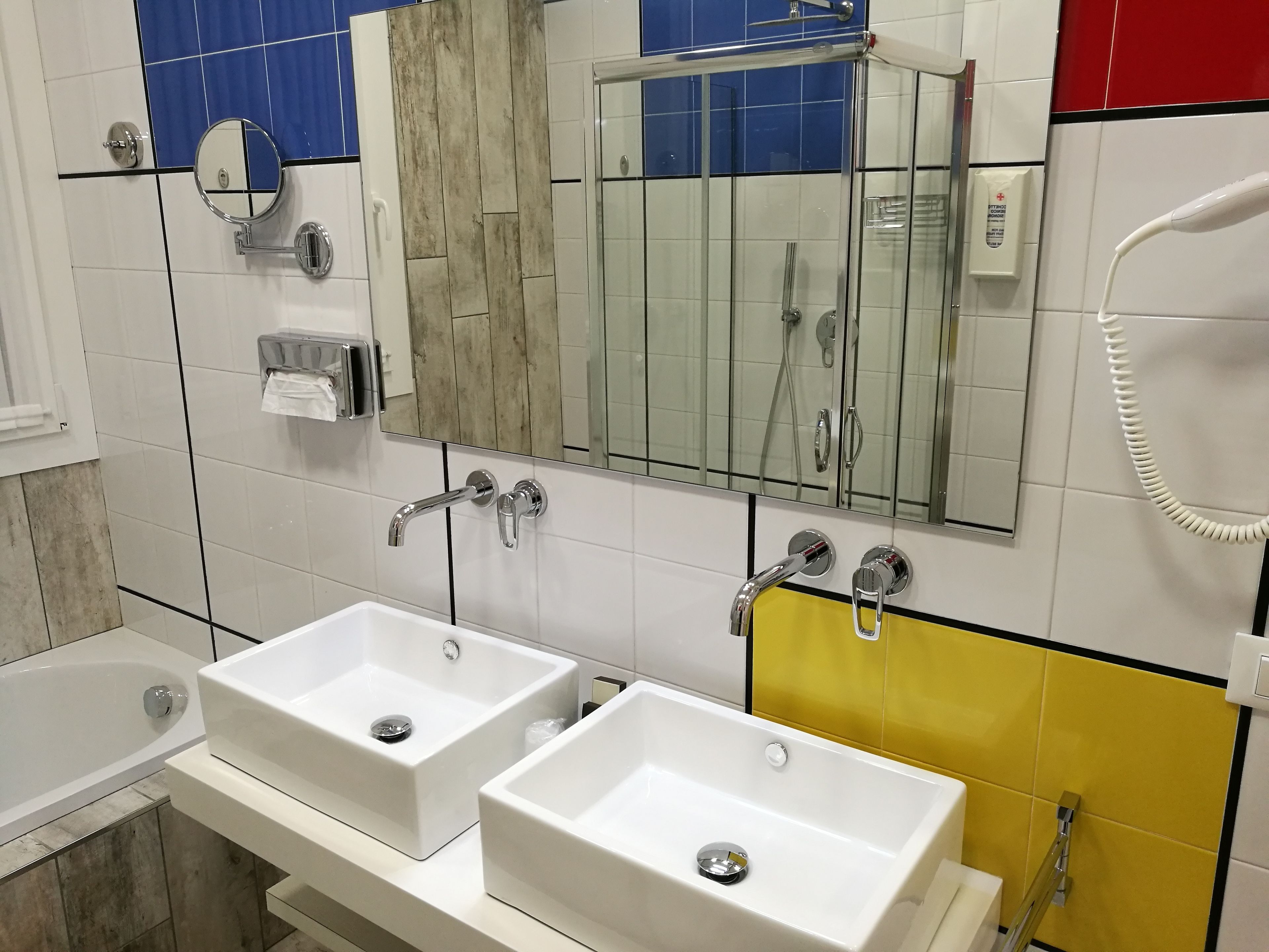 A bathroom with two sinks, a mirror, a shower, and a toilet.