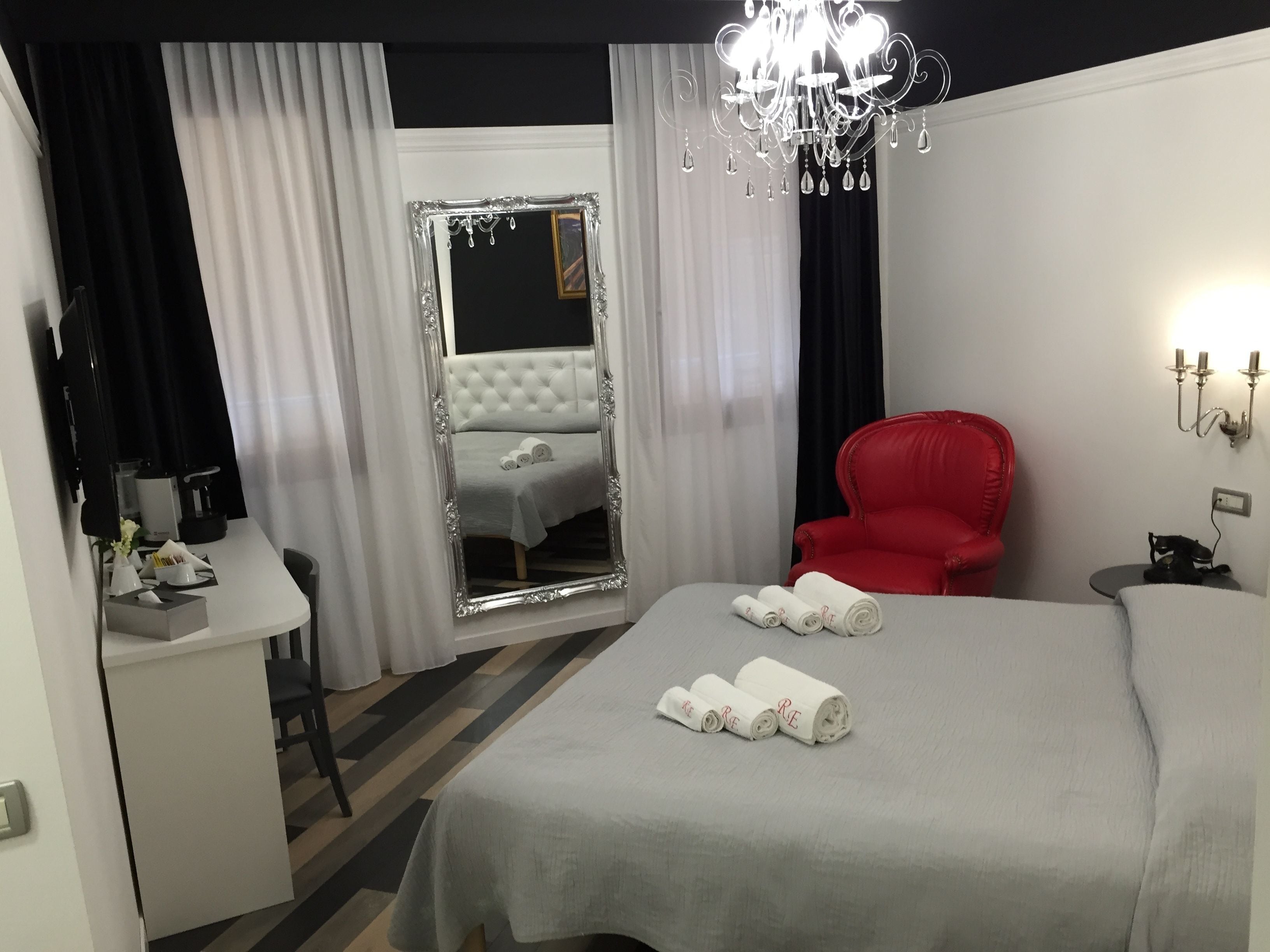 Una habitación de hotel con una cama grande, una silla roja, un escritorio y un espejo.