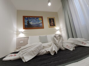 Habitación de hotel con una cama, dos cuadros en la pared y un juego de toallas sobre la cama.