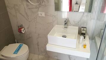 Un bagno con lavandino bianco, WC e zona doccia.