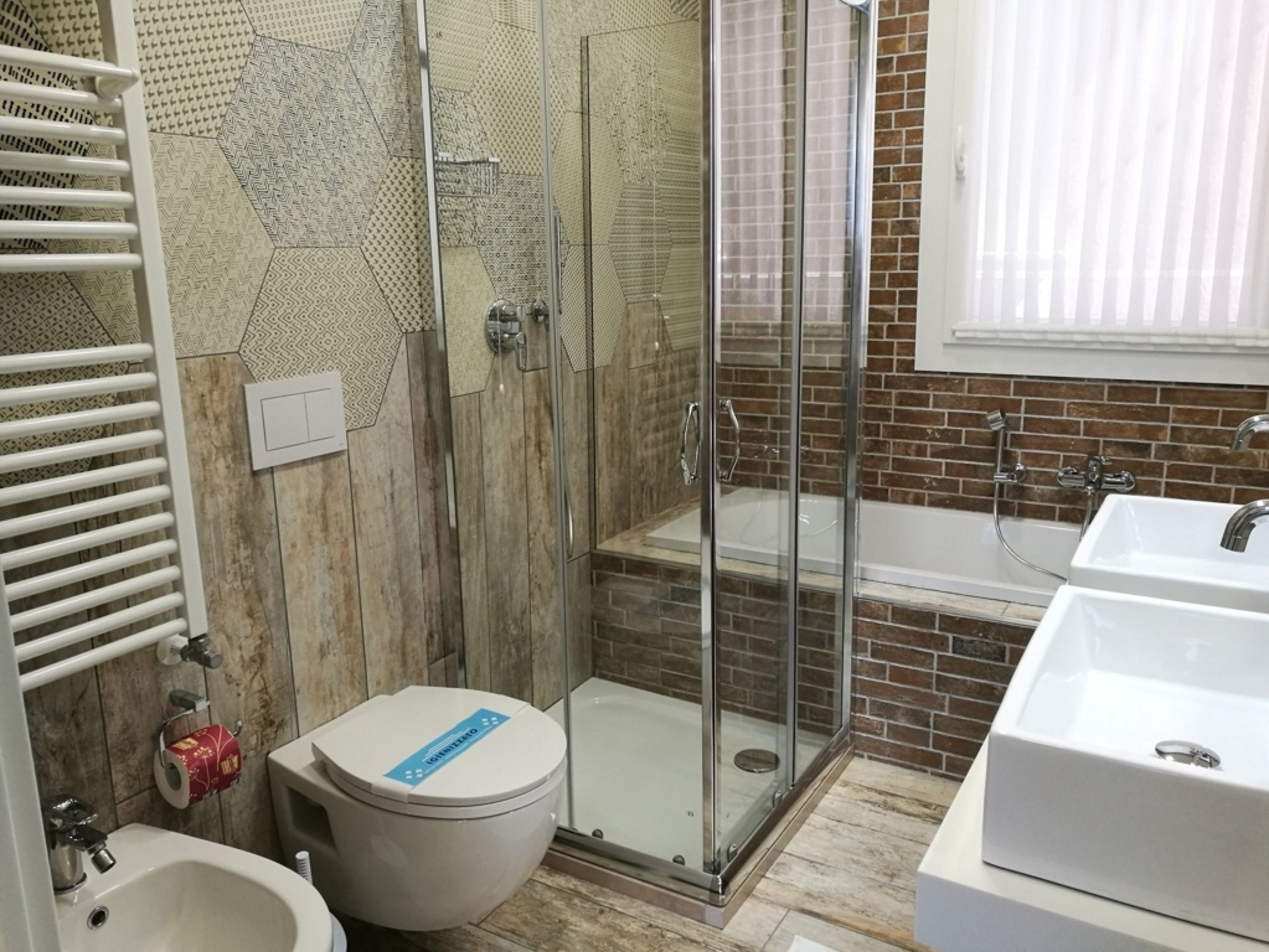 A bathroom with a glass-enclosed shower, a white sink, and a toilet.
