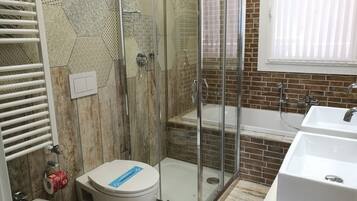 A bathroom with a glass-enclosed shower, a white sink, and a toilet.