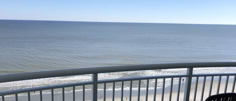 A balcony with a view of the beach and ocean.