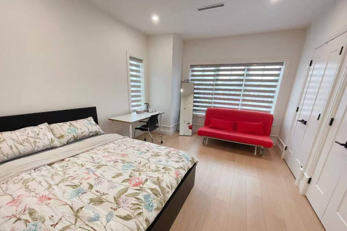 Une chambre à coucher avec un lit, un bureau, un canapé rouge et une armoire.