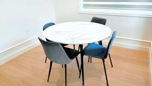 Una mesa redonda con tapa de mármol blanco rodeada por cuatro sillas, una de ellas azul.