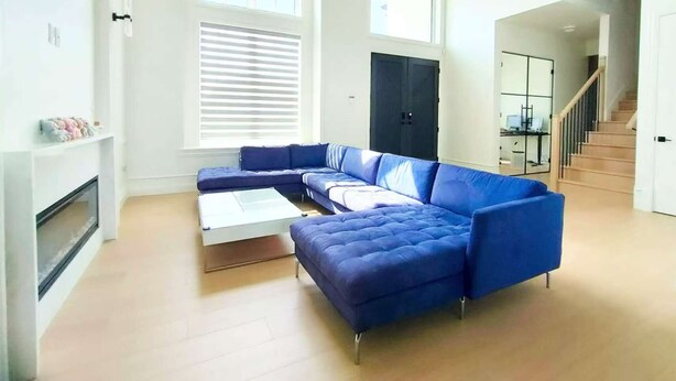 Un amplio salón con un sofá seccional, una chimenea y una escalera que lleva a otro nivel.