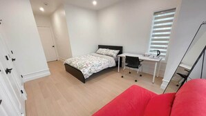 Un dormitorio con una cama, un escritorio, una silla y un sofá rojo.