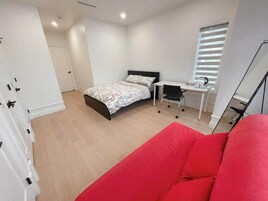 Un dormitorio con una cama, un escritorio, una silla y un sofá rojo.