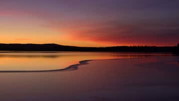 A calm lake at sunset with a forested horizon.