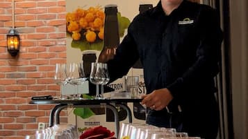 A man standing behind a table with glasses and bottles, a brick wall, and a sign for Northern Brewers.