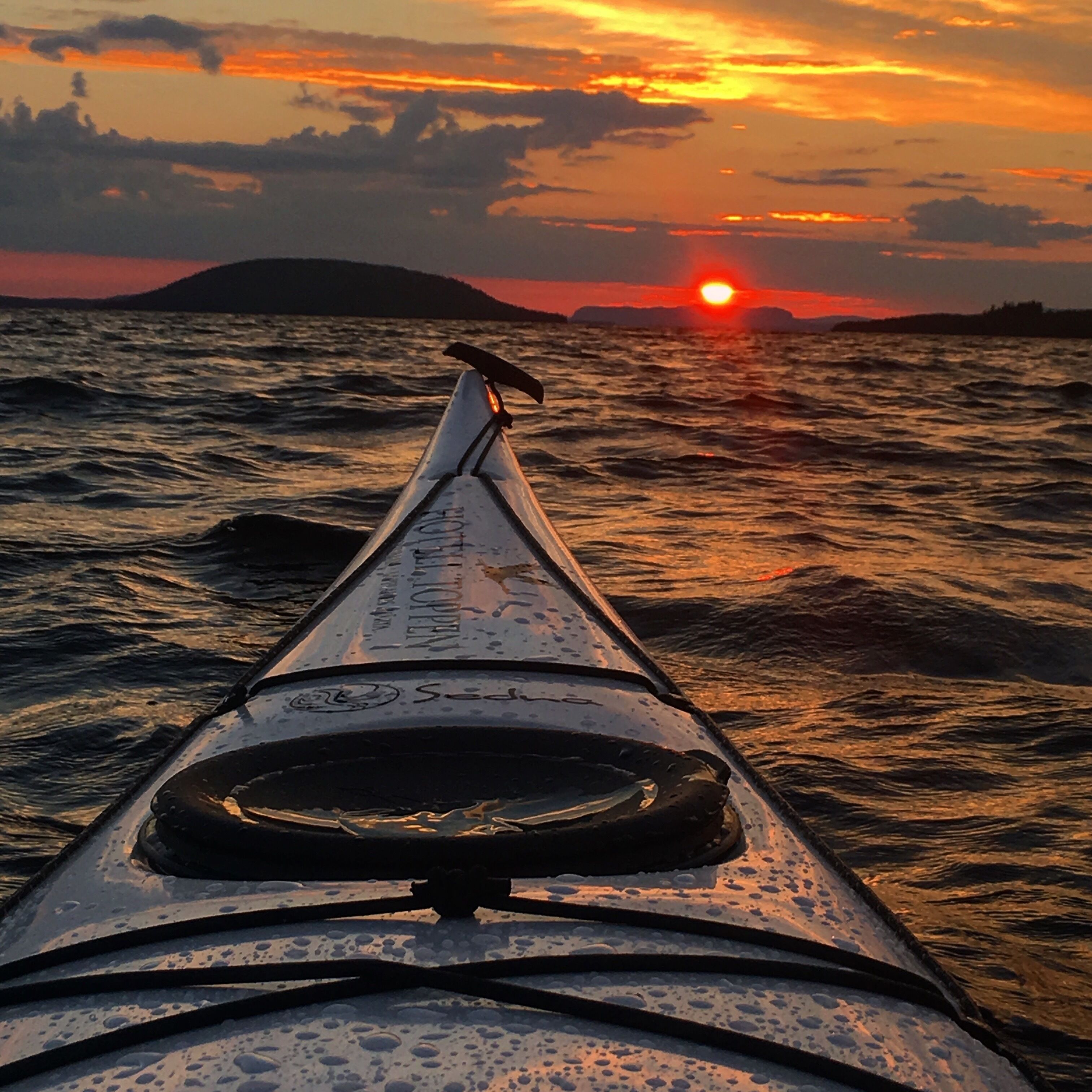 Una canoa en el agua con un atardecer de fondo.