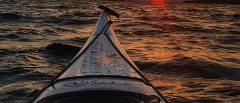 Una canoa en el agua con un atardecer de fondo.