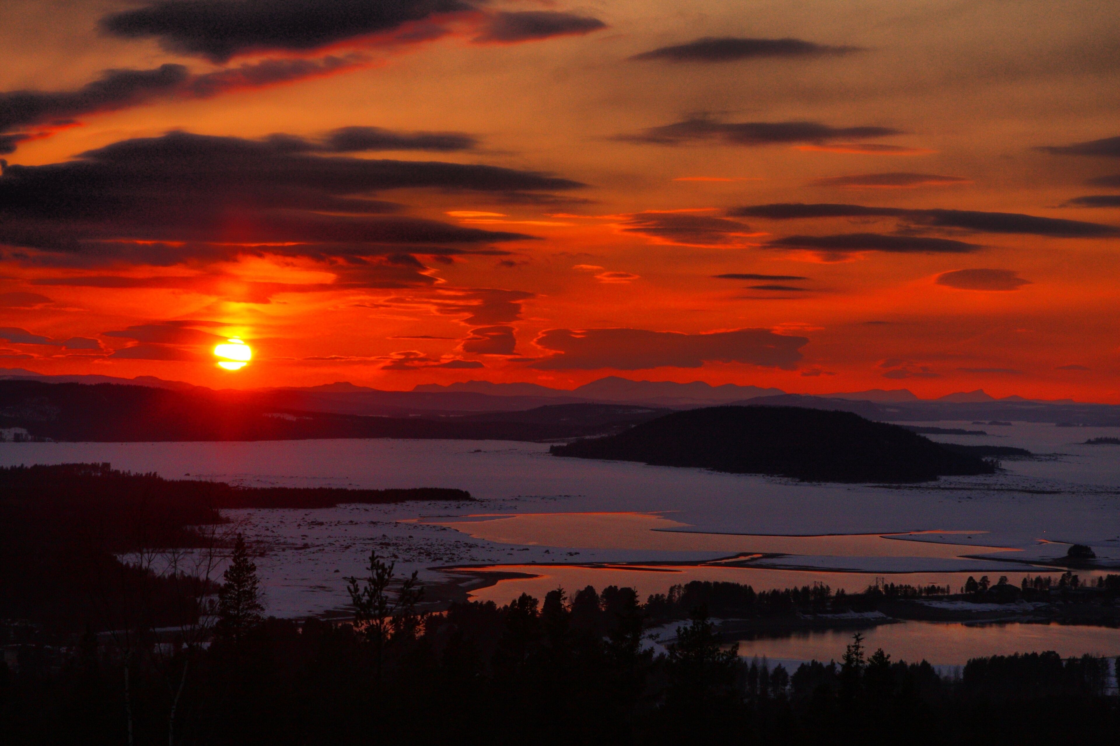 A sunset over a lake with mountains in the background.