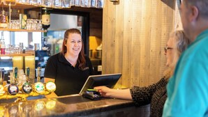 Uma área de bar com balcão, um bartender e um cliente.