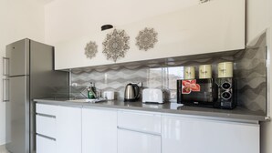 A modern kitchen with a stainless steel refrigerator, a microwave, a toaster, and decorative wall art. - Yafo 35 - Isrentals (Jerusalem)
