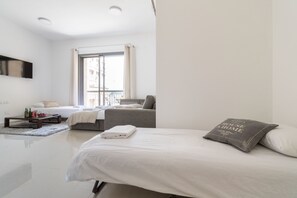Ein modernes Hotelzimmer mit einem großen Bett, einer Sitzecke, einem kleinen Tisch mit Getränken und einem an der Wand montierten Fernseher.