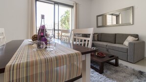 A modern living room with a dining table, a sofa, and a large window. - Yafo 35 - Isrentals (Jerusalem)