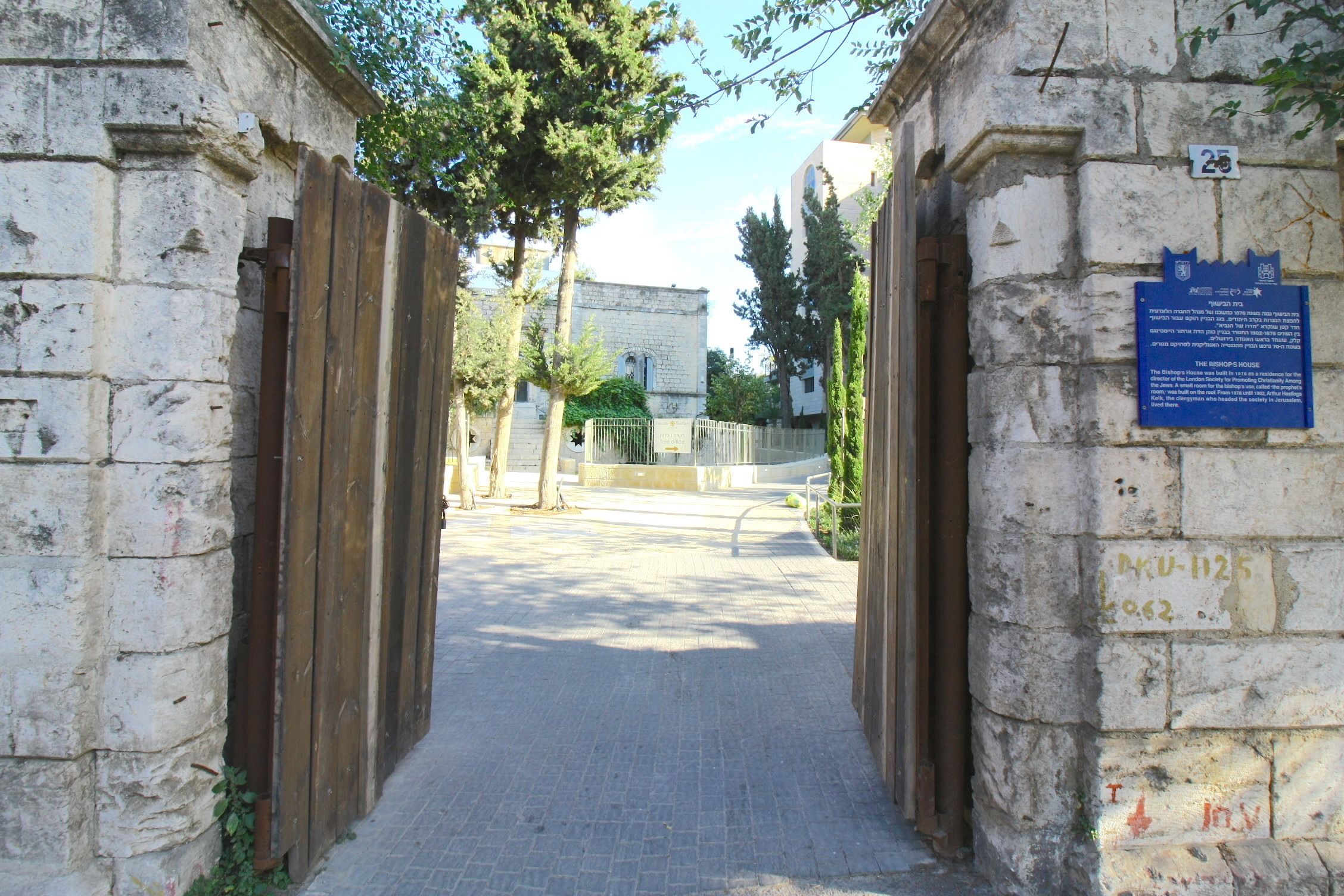 A stone pathway leading to a building with a blue informational plaque.