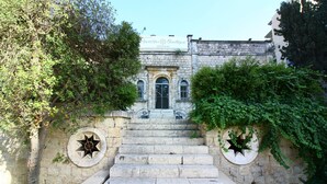 A stone staircase leading to a building with arched windows and a star-shaped window on the left. - The Haneviim Boutique - Isrentals (Jerusalem)