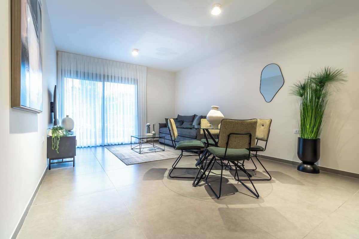Un salon moderne avec un canapé, des fauteuils, une table basse et une plante en pot.