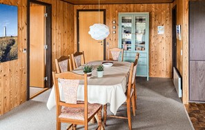 A wooden interior with a dining table, chairs, a cabinet, and a view of the outside.