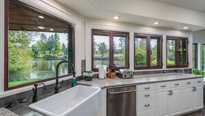 A modern kitchen with a large window, a sink, and a dishwasher. - Bend Waterfront Home: Hot Tub, Walk to Town (Bend)