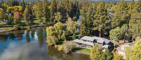 A lakeside property with a large house, a dock, and a well-maintained lawn.