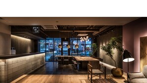 A modern interior with a bar area, seating, and a view through large windows. - BESPOKE HOTEL Shinjuku (Tokyo)