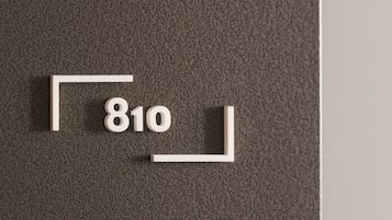 Een geribbelde grijze muur met een witte rechthoekige bord met het cijfer 810 erop.