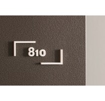 A textured grey wall with a white rectangular sign displaying the number 810.