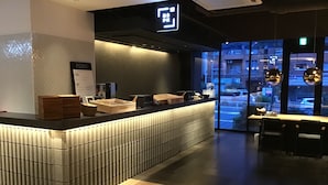 A modern bar area with a counter, seating, and a view of the street outside. - BESPOKE HOTEL Shinjuku (Tokyo)
