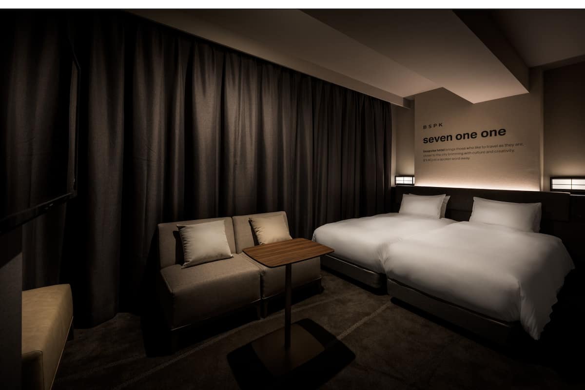 Une chambre d’hôtel avec un lit, un canapé, une petite table et un mur sur lequel est affiché un panneau.