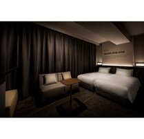 A hotel room with a bed, a sofa, a small table, and a wall with a sign.