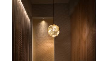 A modern interior with a wooden table and benches, a textured wall, and a hanging light fixture.