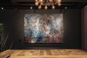 A room with a large abstract painting on the wall, a wooden floor, and a chandelier.