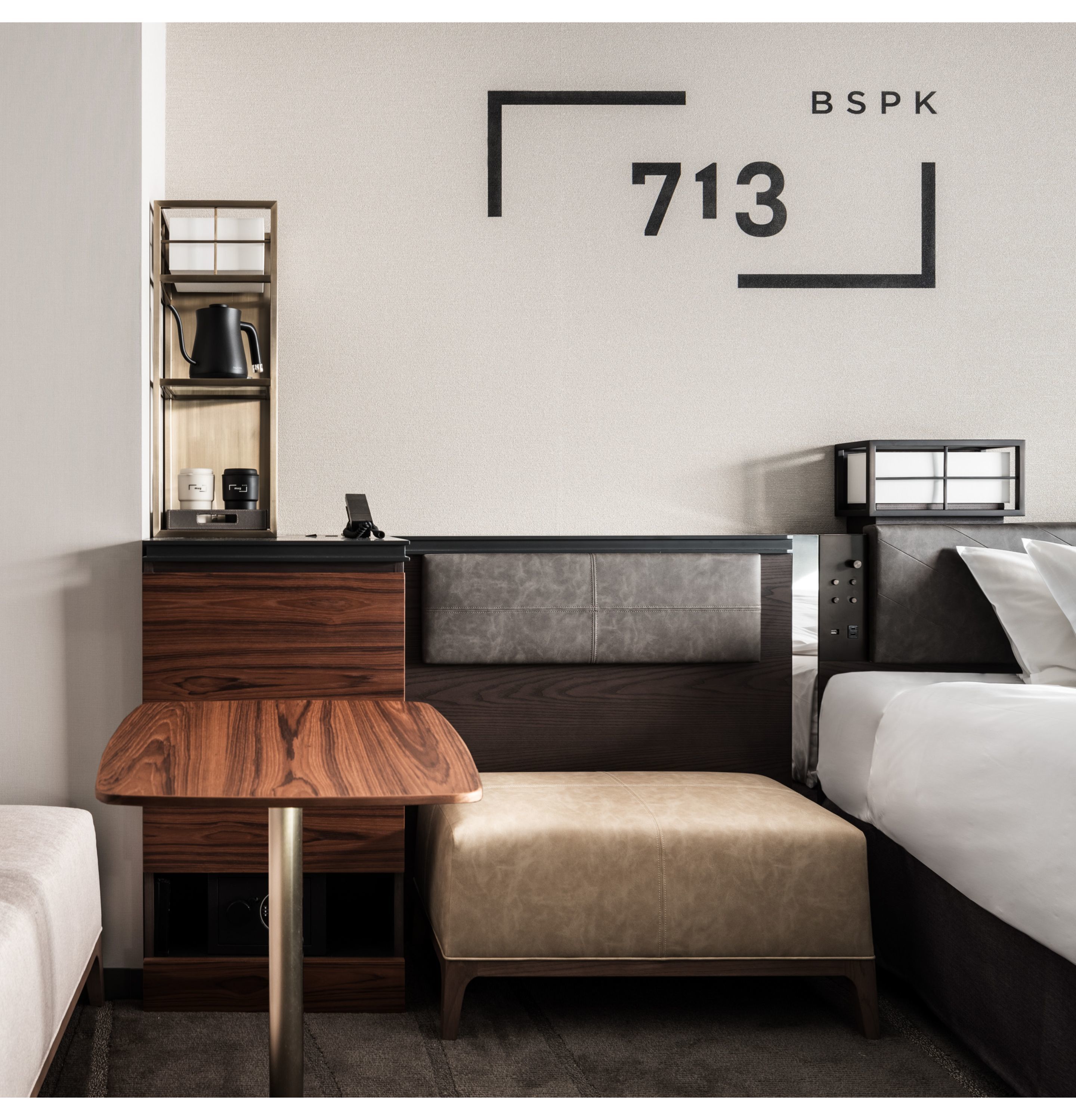 Ein modernes Hotelzimmer mit einem Holztisch, einer Couch, einem Bett und einer Minibar.