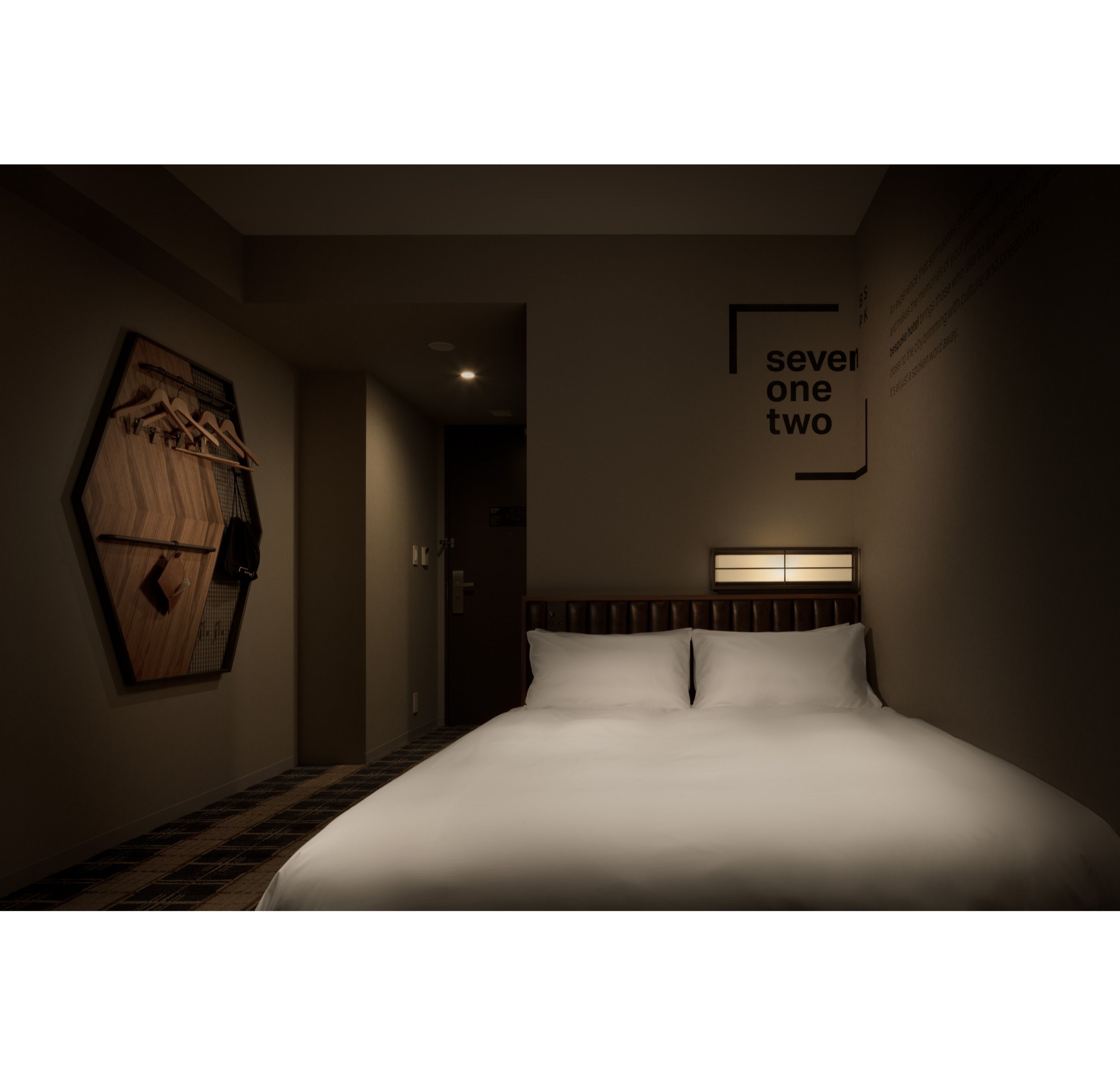 Ein Hotelzimmer mit einem großen Bett, einer Holzwandkunst und einem Schild an der Wand.