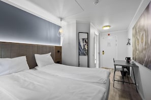 A hotel room with two beds, a desk, and a large painting on the wall.