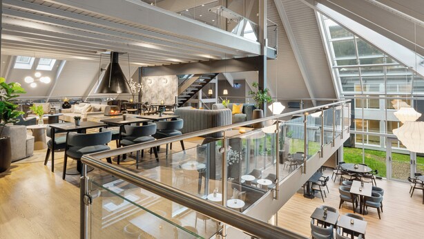 A modern interior with a glass railing, multiple dining areas, and a staircase leading to an upper level. - Thon Hotel Partner Mo i Rana (Mo-I-Rana)