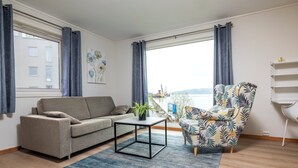A living room with a sofa, a patterned armchair, a coffee table, and a view of the sea. - Thon Hotel Partner Mo i Rana (Mo-I-Rana)