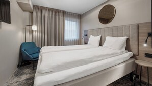 A hotel room with a large bed, a blue chair, a round mirror, and a small table. - Thon Hotel Partner Mo i Rana (Mo-I-Rana)
