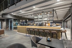 Un área de bar moderna con mostrador, taburetes e iluminación colgante.