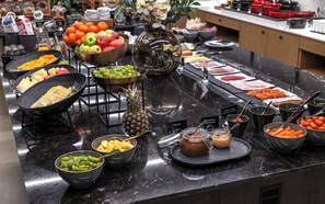Un bufé con diversas frutas, verduras y platos preparados.