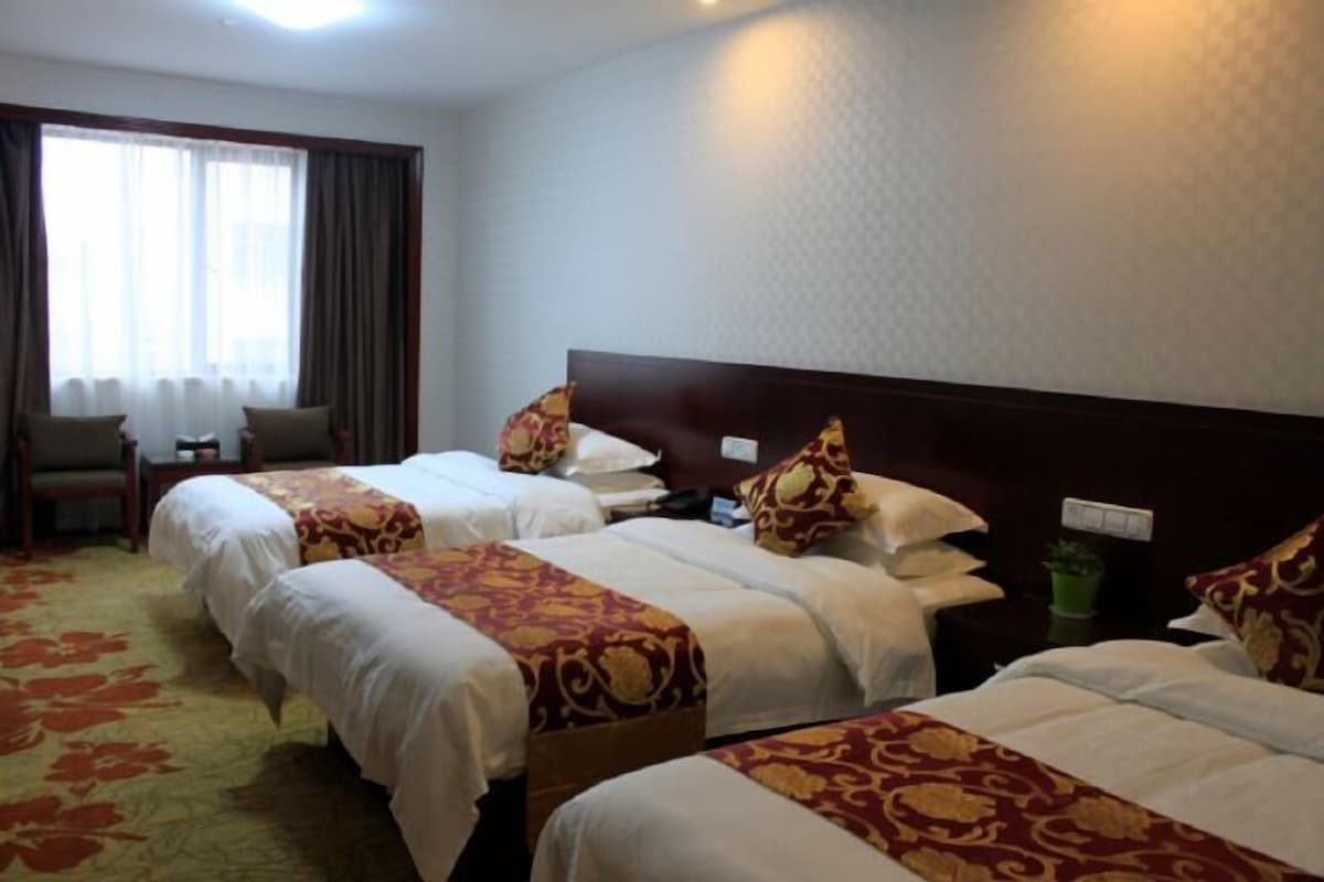 A hotel room with two beds, a desk, and a chair.