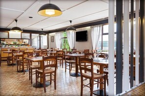 A restaurant with wooden tables and chairs, a tiled floor, pendant lights, and a buffet area.