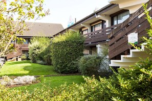 Ein Hotel mit gepflegtem Garten, einer Holztreppe und einem Schild mit den Zimmernummern.