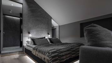 Un dormitorio moderno con cama, dos lámparas de noche, un ventanal grande y un sillón gris.