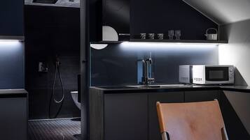 Cocina compacta con microondas, pileta y una silla.
