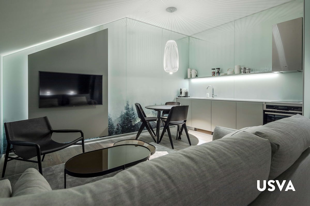 Un salon moderne comprenant un canapé, une table basse, un téléviseur et un coin repas avec des chaises et une table.
