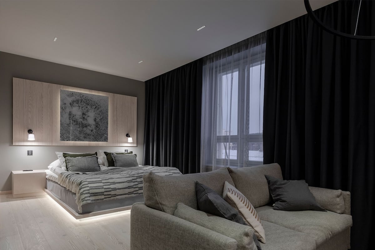 Une chambre moderne avec un lit, un canapé et une grande fenêtre avec des rideaux.